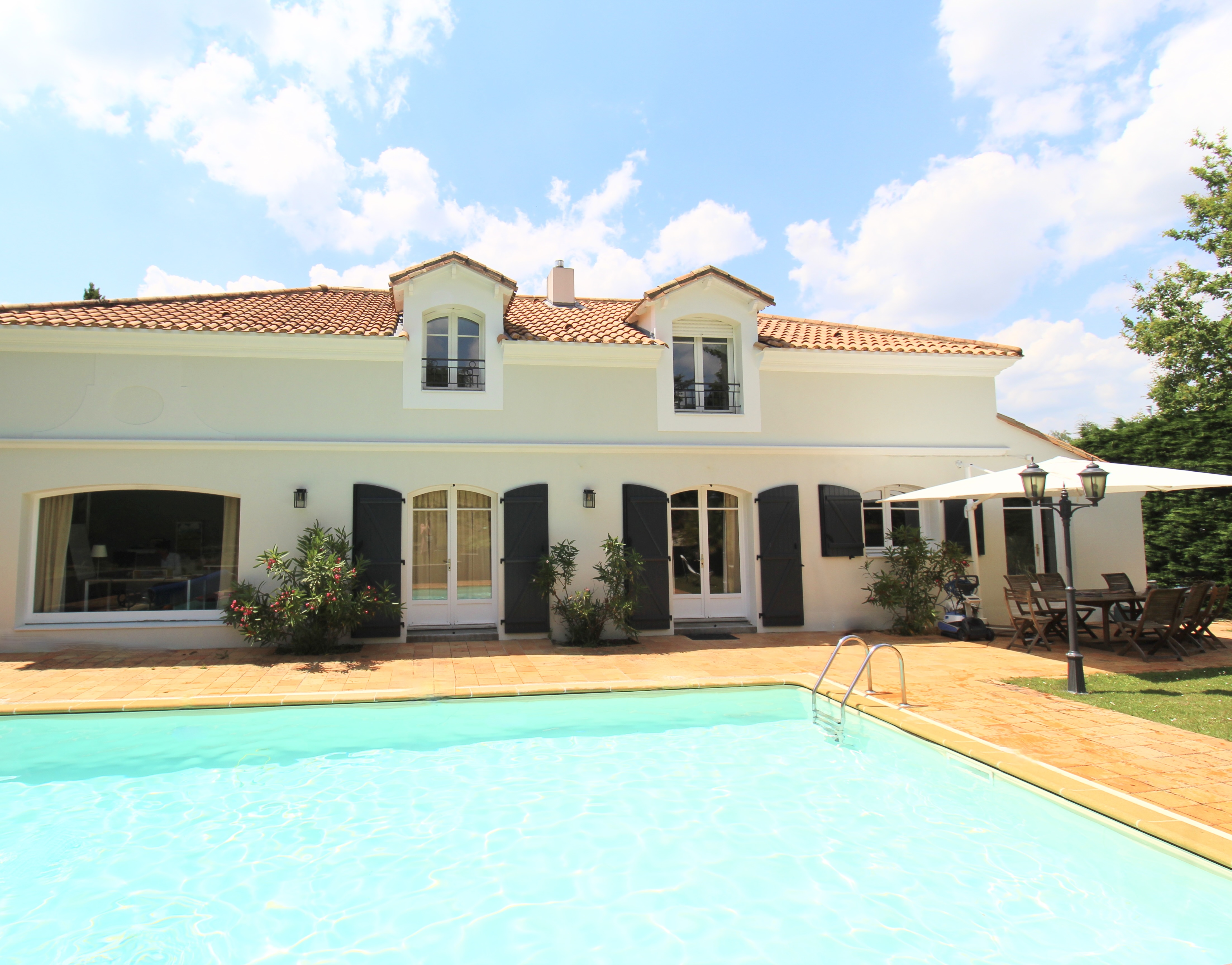 Maison familiale moderne avec piscine, terrasse et volets noirs