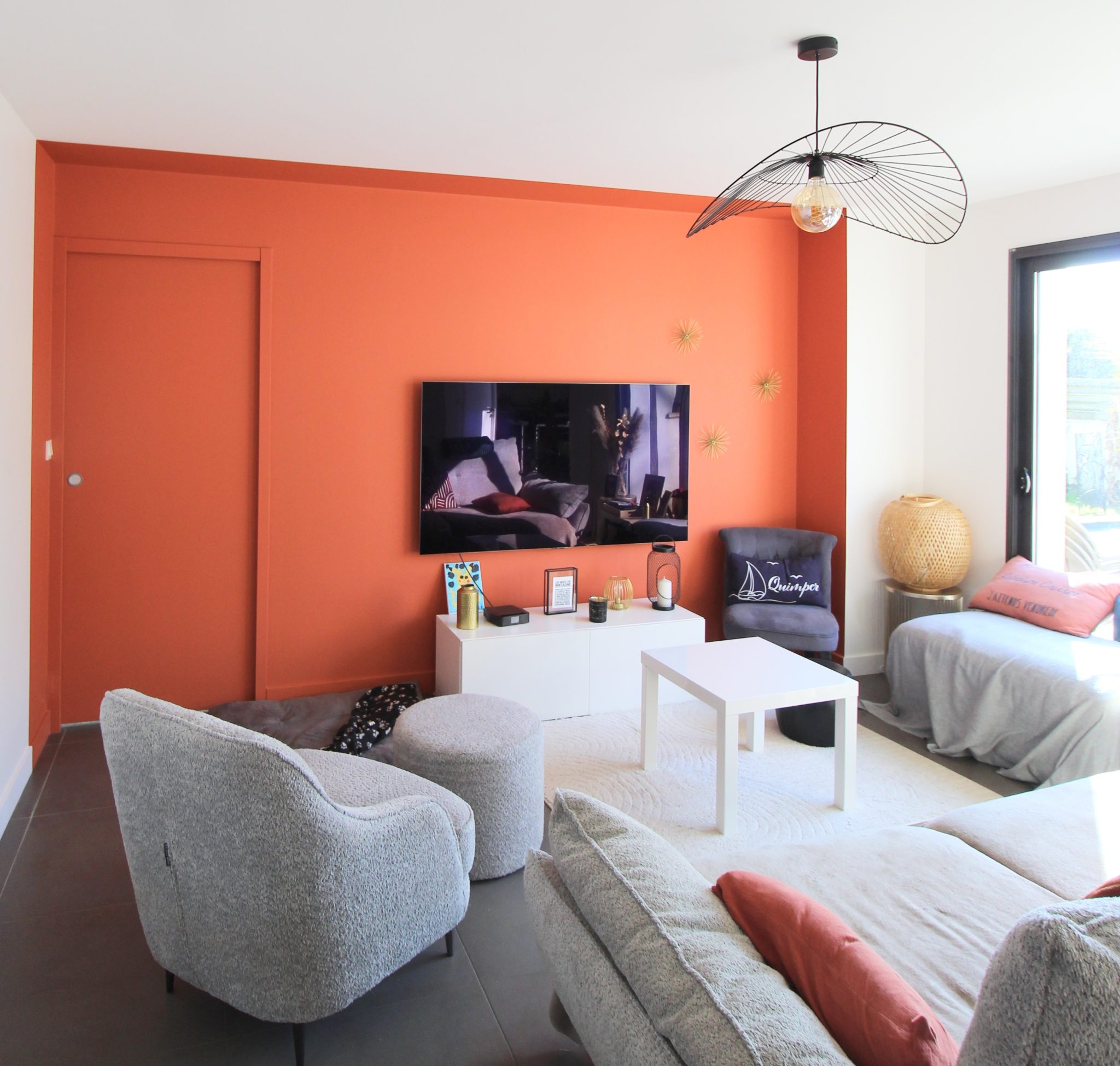 Salon moderne avec mur orange, canapé gris et décoration contemporaine
