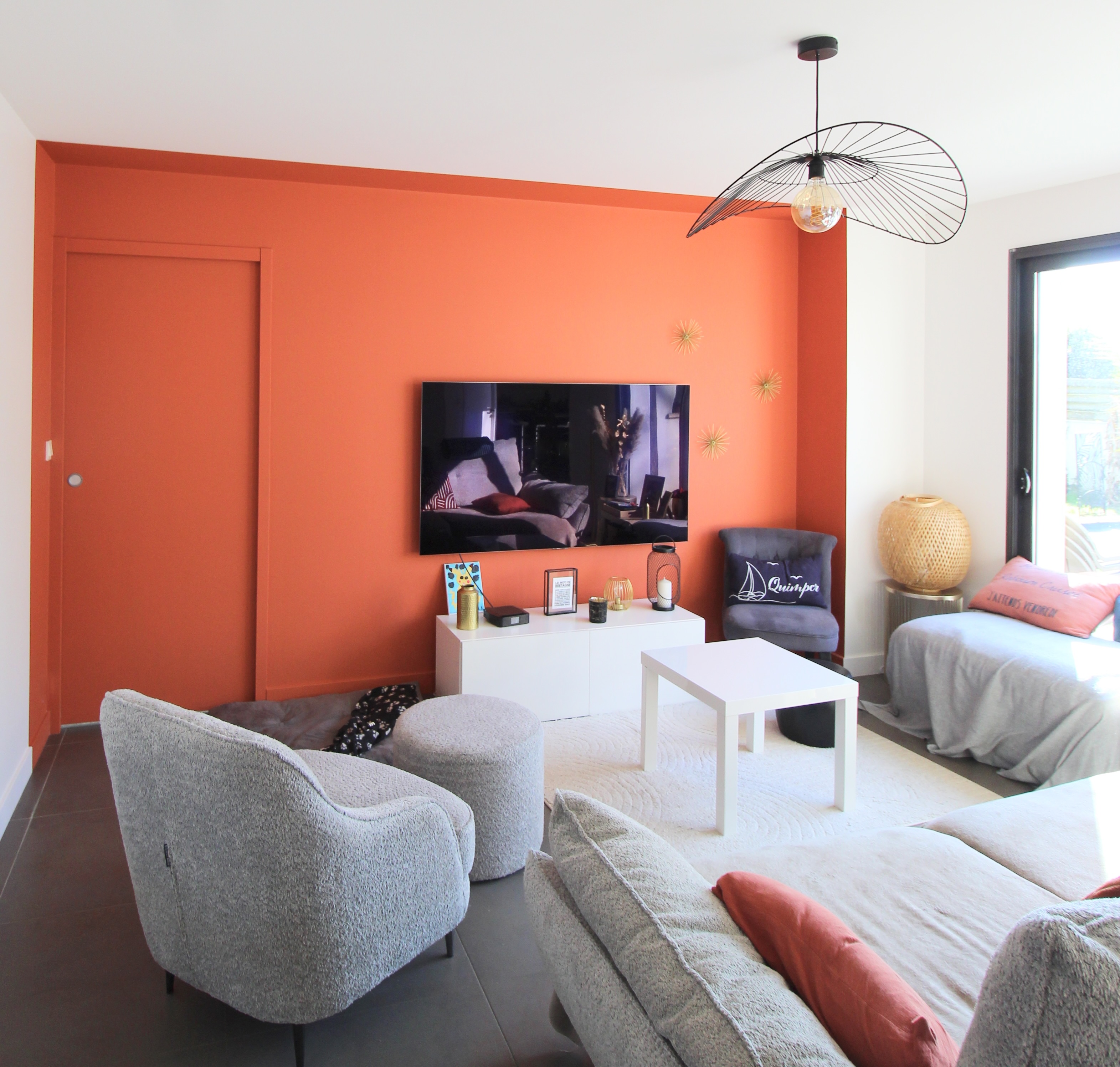 Salon moderne avec mur orange, canapé gris et décoration contemporaine