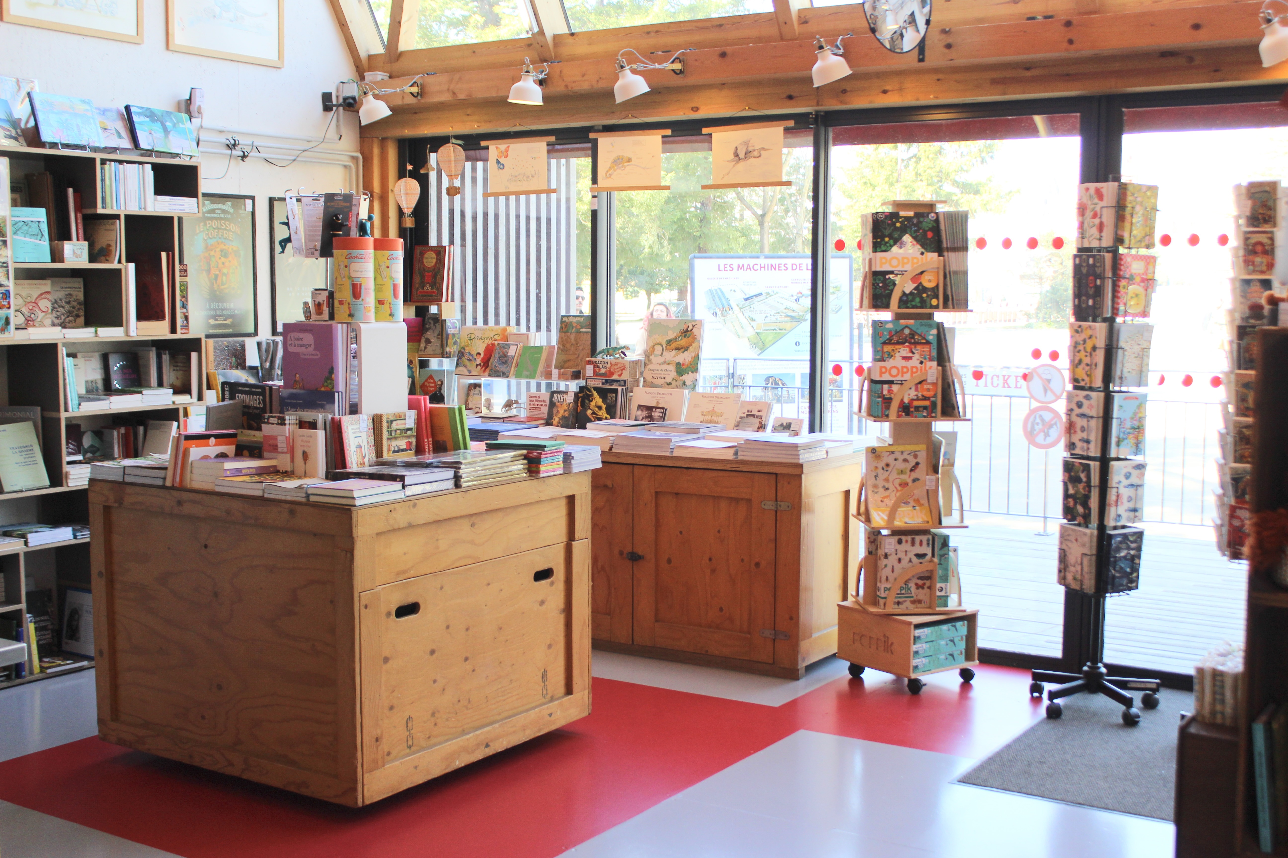 Intérieur d’une librairie avec présentoirs en bois, livres et cartes postales
