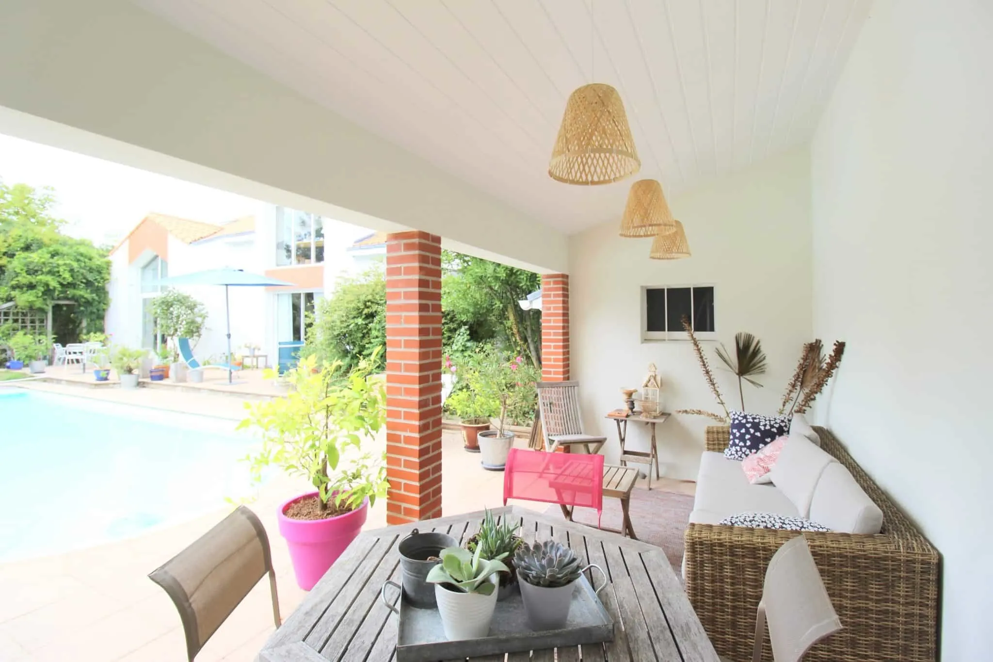Terrasse couverte décorée avec mobilier et vue sur la piscine d’une maison moderne