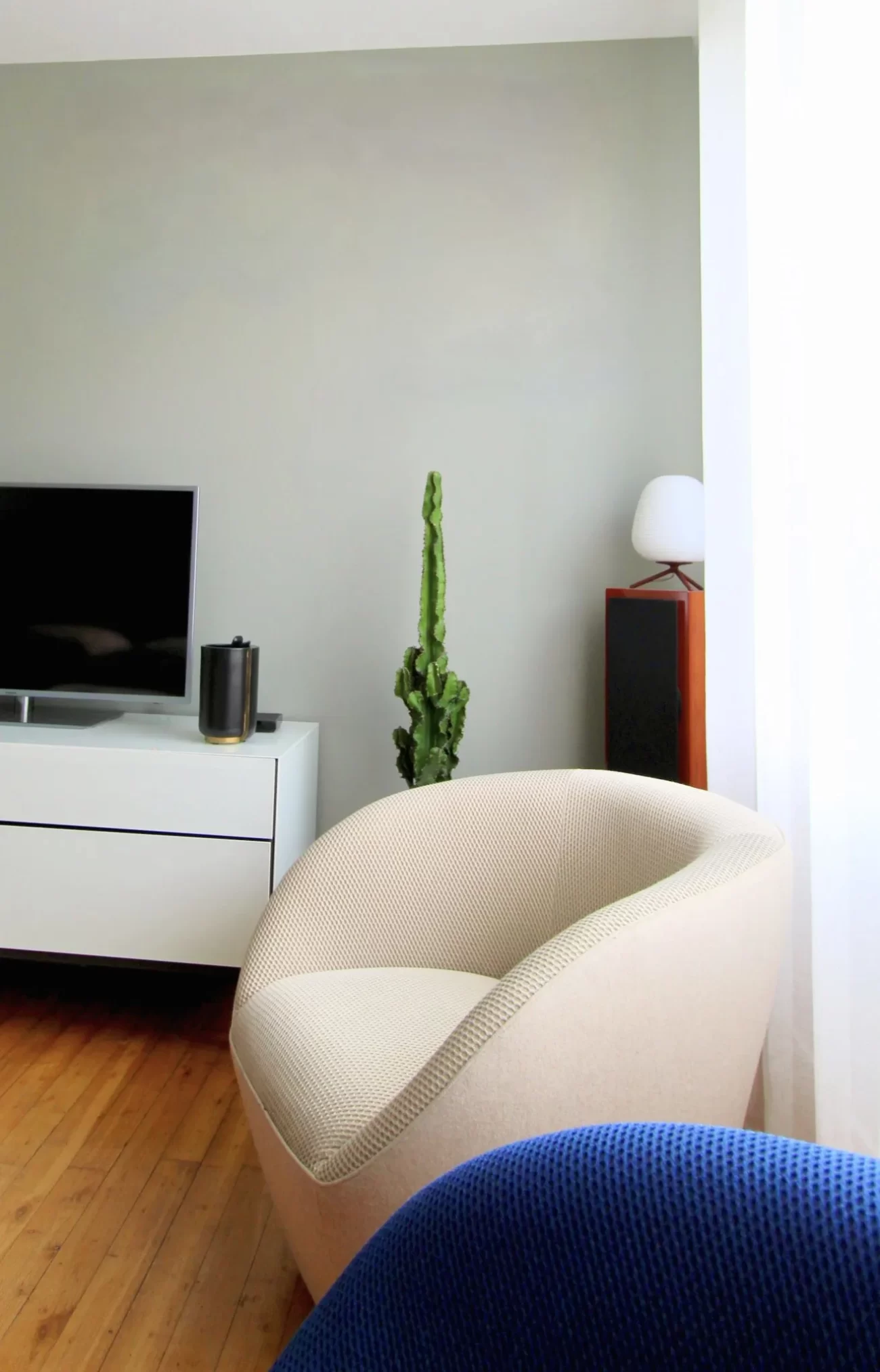 Salon moderne avec fauteuil design beige, meuble TV blanc et décoration minimaliste